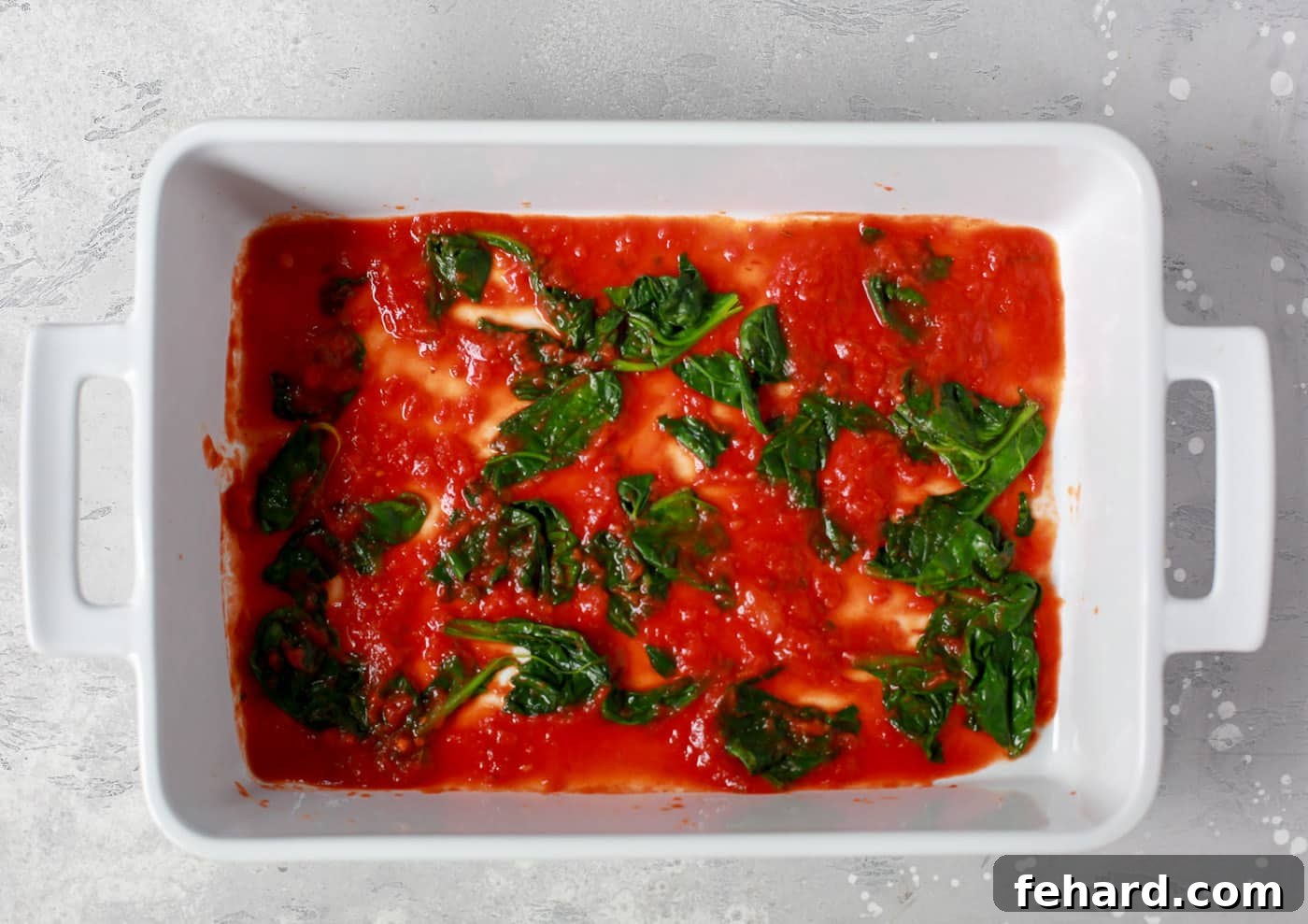 Zucchini Ribbon Bake 3 overhead view of a white casserole containing tomato sauce and spinach