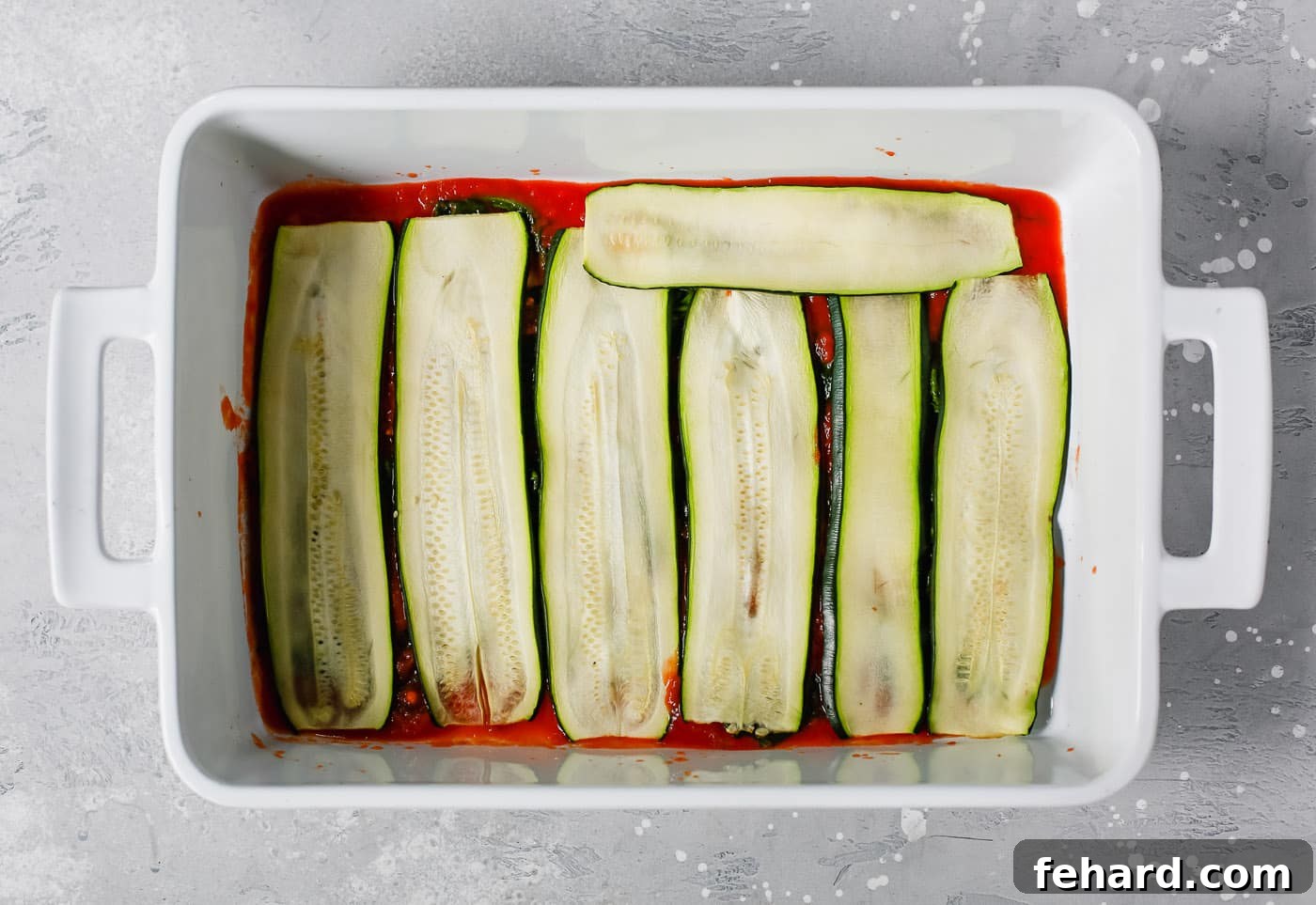 Zucchini Ribbon Bake 4 overhead view of a white casserole containing tomato sauce and zucchini noodles