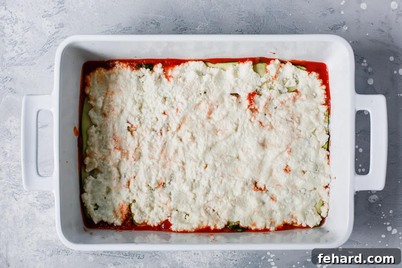 Zucchini Ribbon Bake 5 overhead view of a white casserole containing tomato sauce, zucchini noodles and ricotta