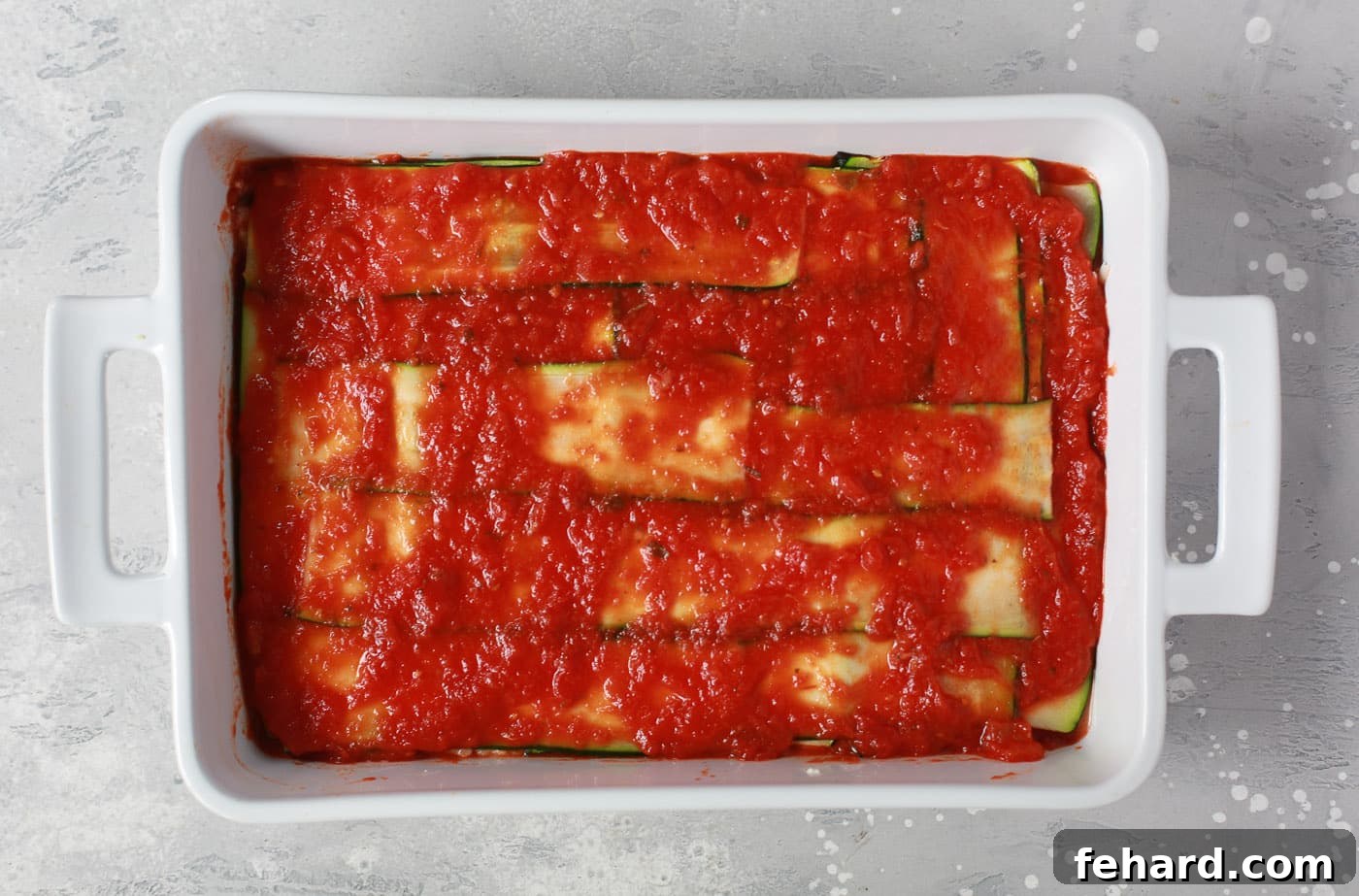 Zucchini Ribbon Bake 7 overhead view of a white casserole containing zucchini noodles and tomato sauce