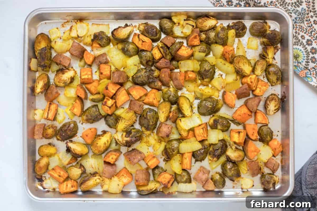 Roasted Fall Veggies Ready Beautifully roasted fall vegetables, including sweet potatoes, Brussels sprouts, and onions, on a rimmed sheet pan, golden-brown and tender.