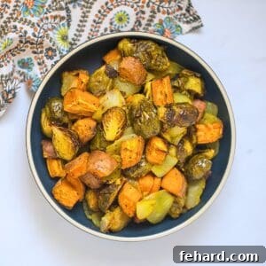 Roasted Fall Vegetables made with Brussels sprouts, onions, and sweet potatoes in blue bowl.