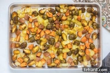 Roasted Fall vegetables with sweet potatoes, Brussels sprouts, and onions on rimmed sheet pan.