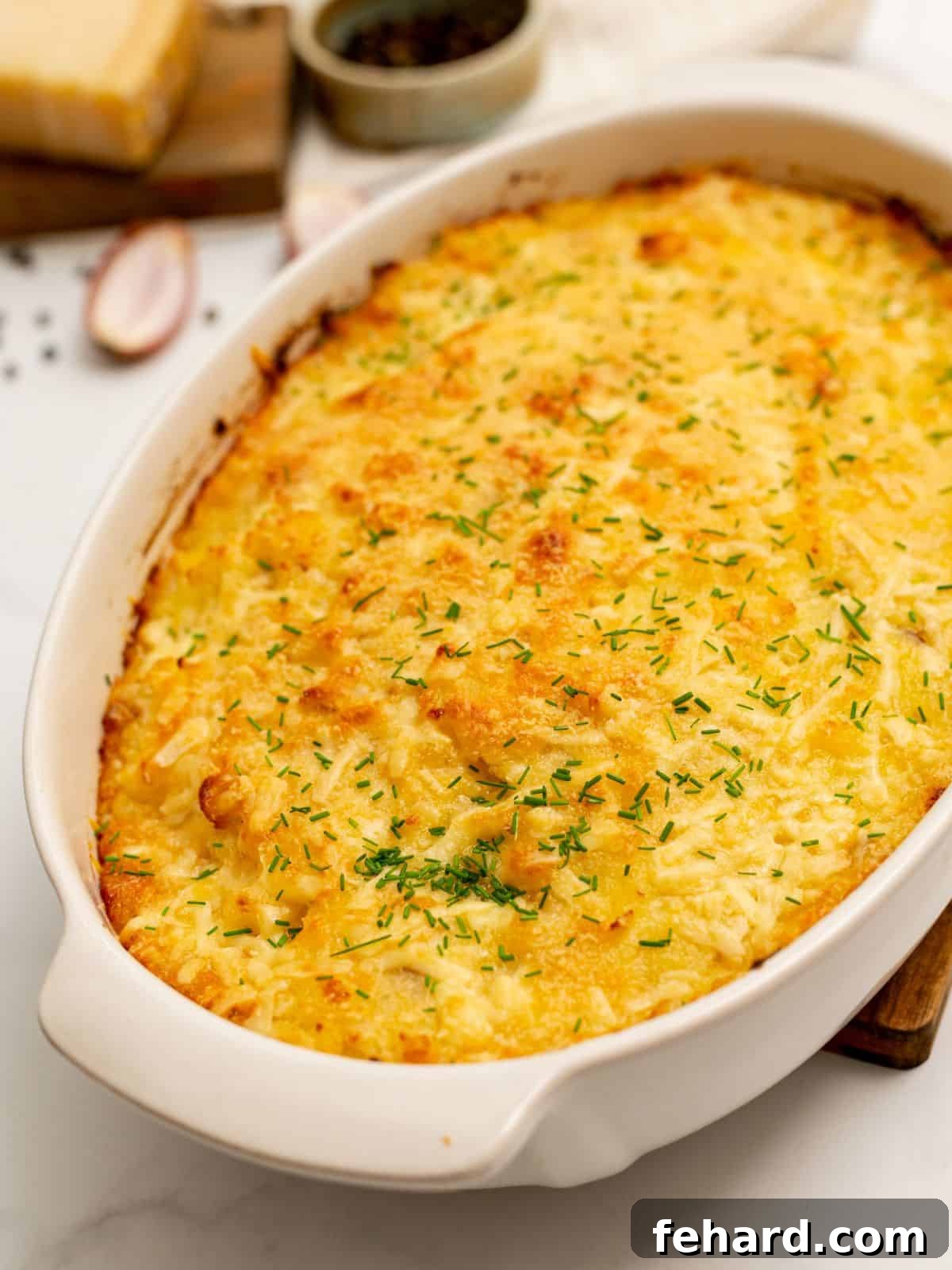 Classic Potatoes Romanoff Casserole Potatoes Romanoff baked in a elegant white casserole dish, garnished with fresh minced chives, ready to serve.