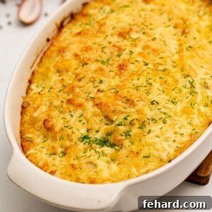 Baked Cheesy Potatoes Romanoff in casserole topped with minced chives.