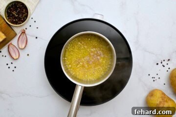 Small saucepan showing melted butter with sauteed shallot and garlic.