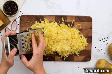 Baked potatoes being grated on box grater with skin left on.