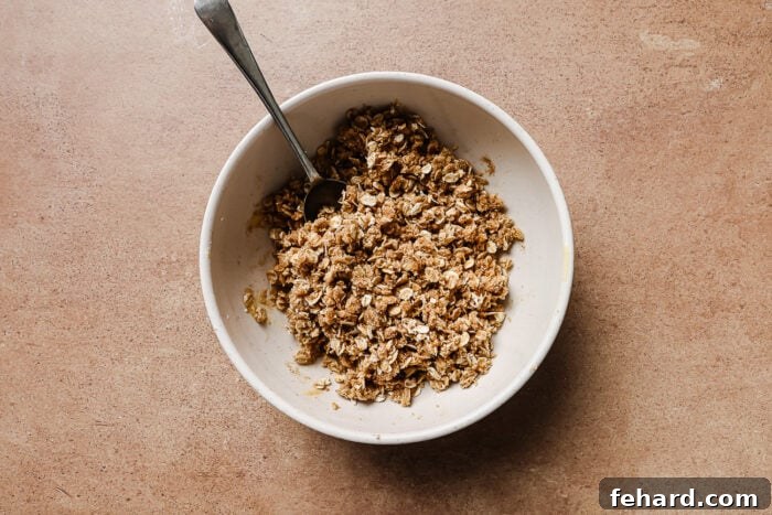 Warm Spiced Gluten Free Apple Crumble 6 Almond flour, rolled oats, and sugar mixed in a white bowl to create a crunchy apple crisp topping.