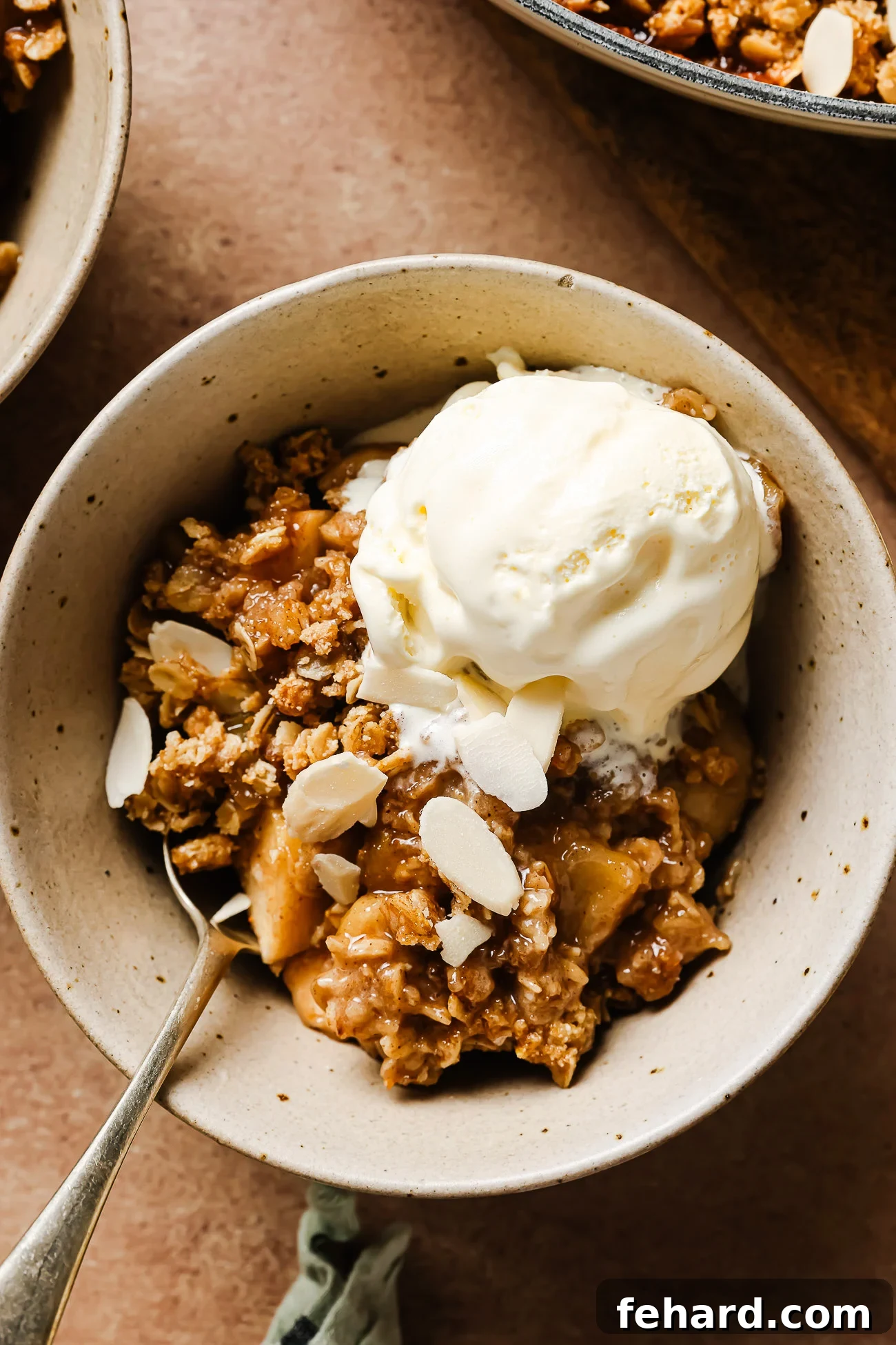 Warm Spiced Gluten Free Apple Crumble 8 Gluten-free apple crisp in a white bowl topped with creamy vanilla ice cream for a cozy dessert.