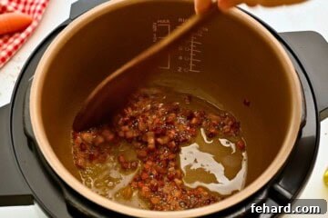 Rich & Rapid Instant Pot Bolognese 4 Wooden spoon pushing around browned cubed pancetta inside inner pot for base of Bolognese sauce.