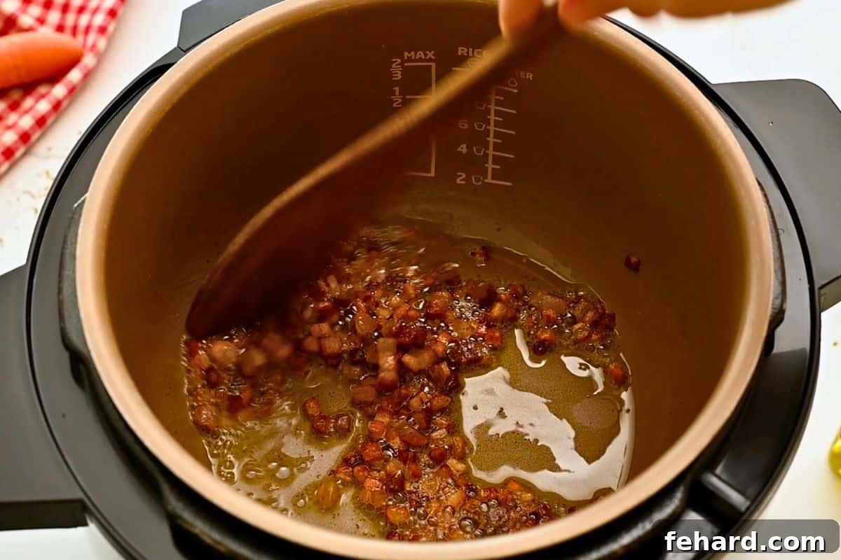 Pressure Cooker Bolognese Sauce Wooden spoon pushing around browned cubed pancetta inside inner pot for base of Bolognese sauce.