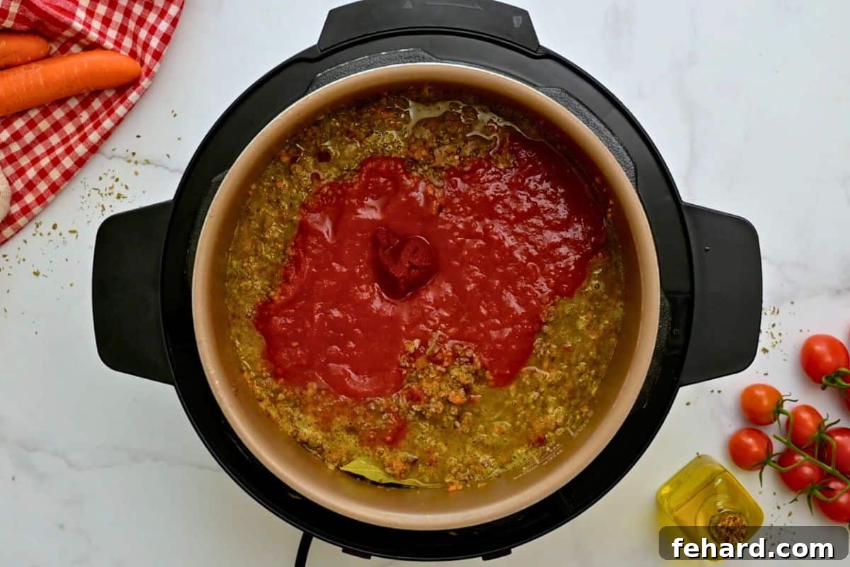 Instant Pot Bolognese with Pancetta Layered meat sauce with tomatoes and tomato paste inside inner pot before pressure cooking Bolognese sauce.