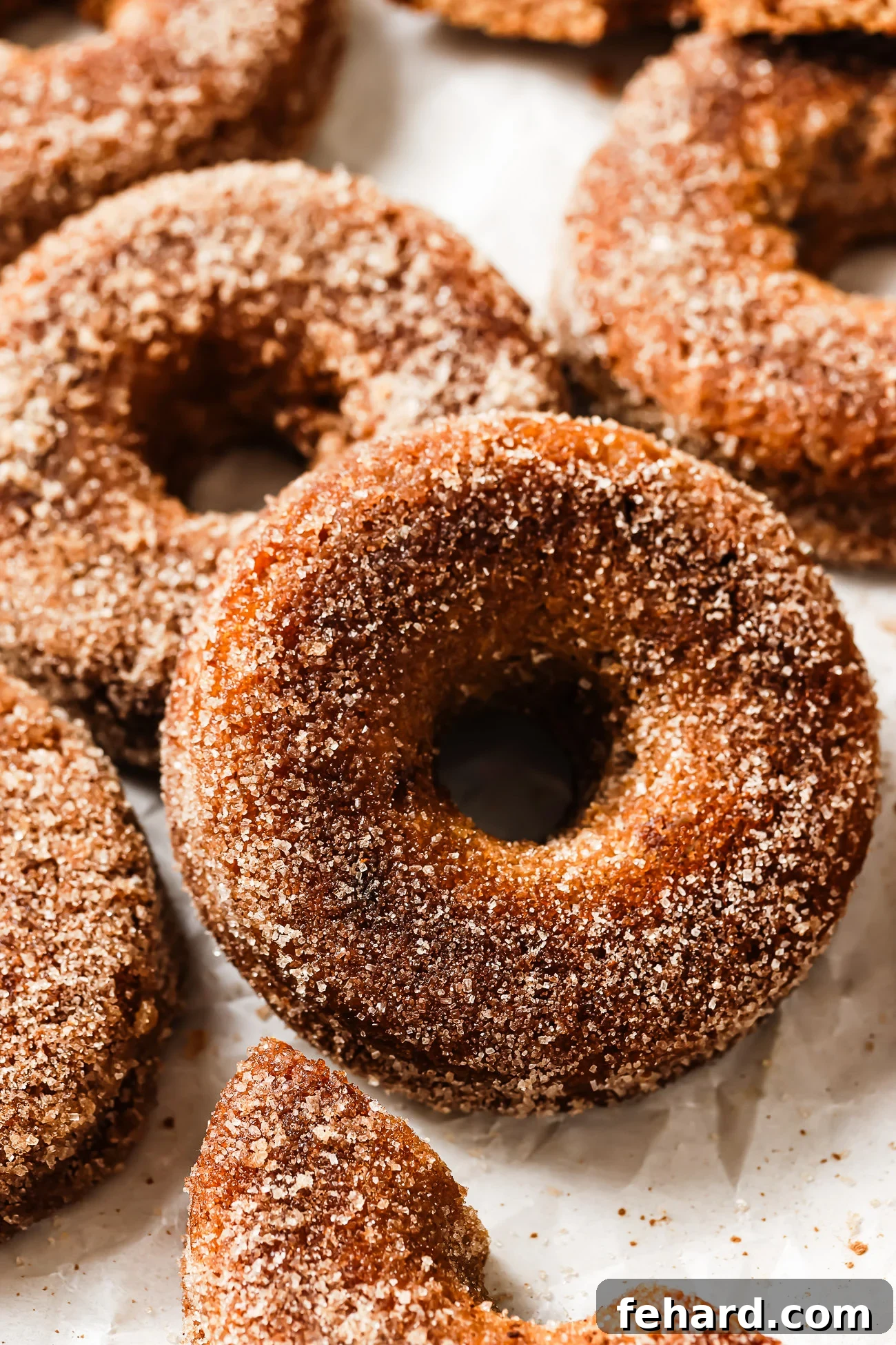 An inviting display of gluten-free apple cider donuts on a kitchen countertop, showcasing their golden-brown hue and glistening cinnamon-sugar coating.