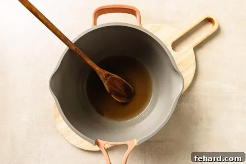 Warm apple cider simmering inside a saucepan.