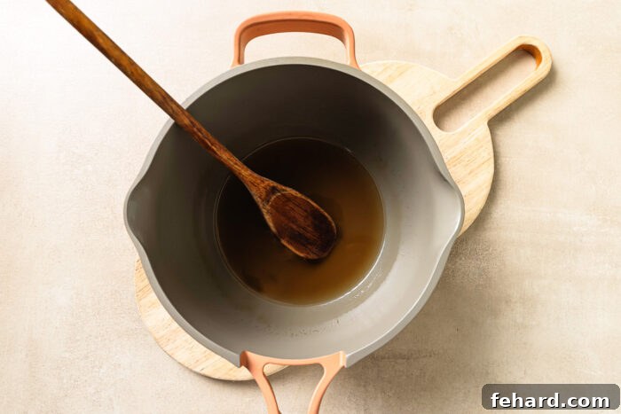 Warm apple cider simmering inside a saucepan, reducing to concentrate its flavor.