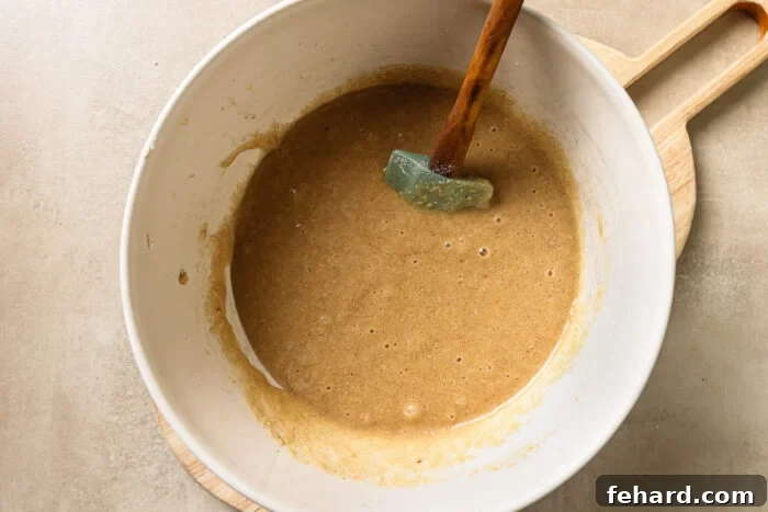 Wet and dry ingredients inside a mixing bowl, just combined to form a thick donut batter.