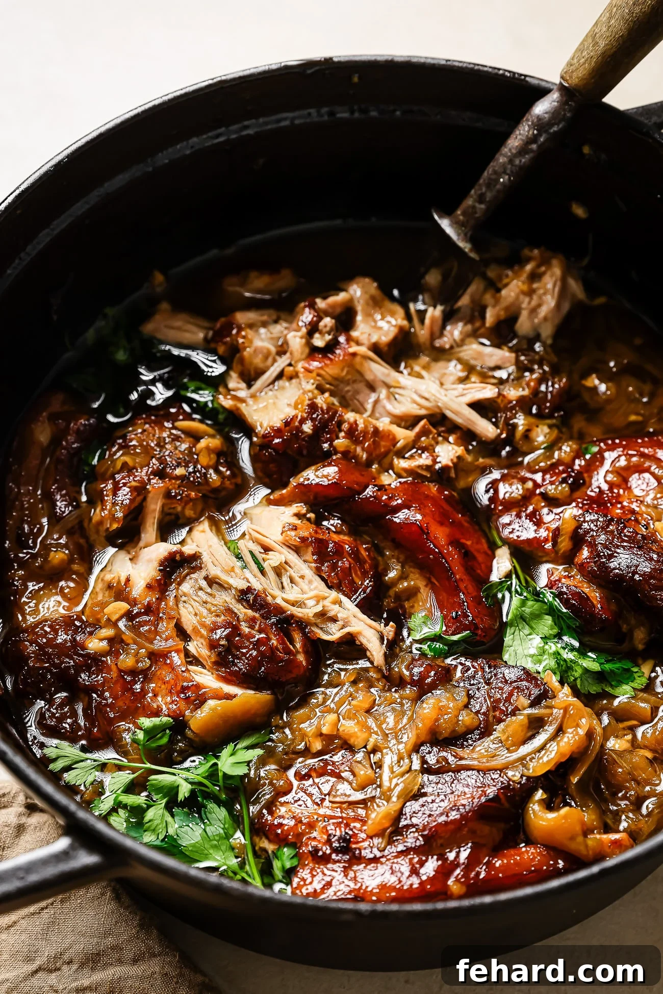 Close-up of Apple Cider Braised Pork Shoulder in a black Dutch oven.