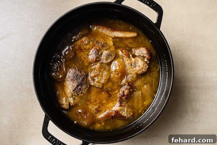 overhead view of apple cider braised pork shoulder in a black Dutch oven pot. 
