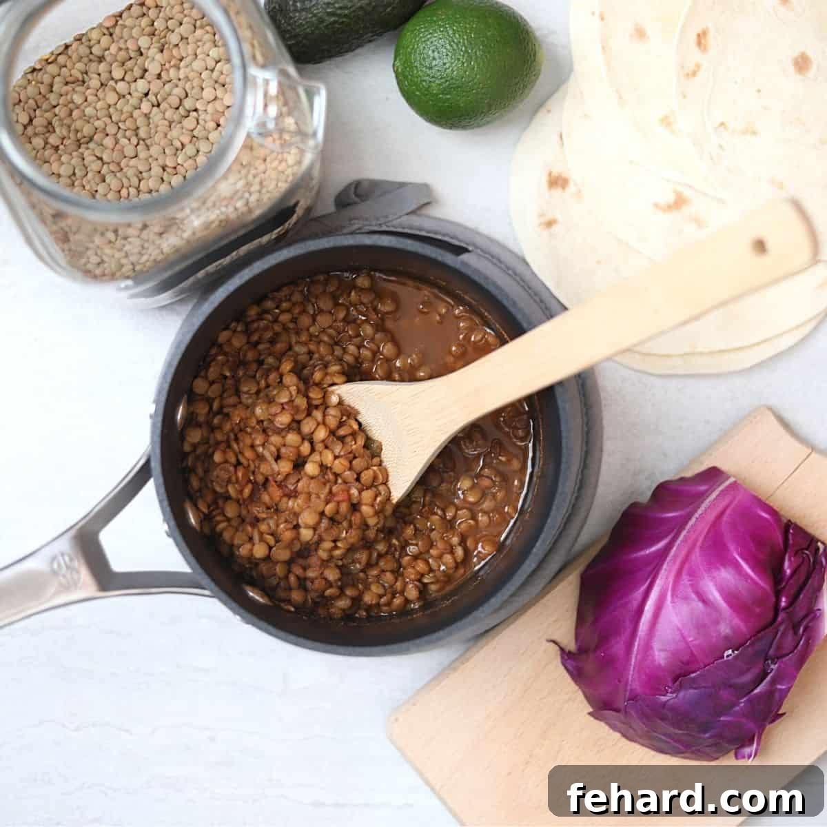 Perfectly cooked lentil taco filling in a saucepan, ready to be served, alongside an array of fresh taco toppings.