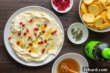 Velvet Brie Whip 4 Whipped brie cheese spread out in white serving dish topped with honey, thyme leaves, pomegranate seeds, and olive oil served with crostini on the side.