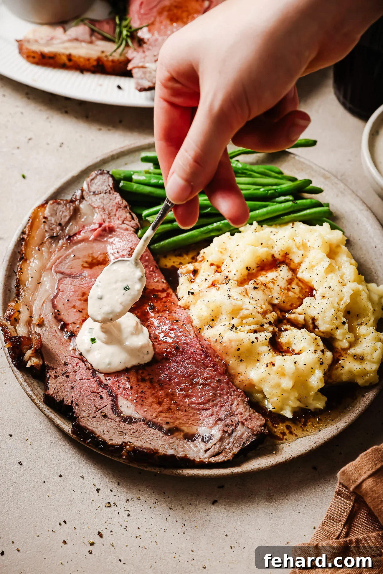 Prime rib plated with mashed potatoes, green beans, and creamy horseradish sauce — a perfect holiday dinner.