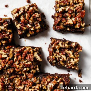 Pecan Pie Swirl Brownies 12 Overhead view of pecan pie brownies cut into squares on parchment paper, featuring a gooey chocolate base and caramelized pecan topping.