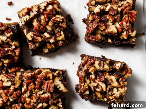 Pecan Pie Swirl Brownies 18 Overhead view of pecan pie brownies cut into squares on parchment paper, featuring a gooey chocolate base and caramelized pecan topping.