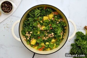 Kale and potatoes added to simmering broth to make soup.