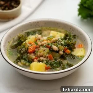 Bowl of homemade white bean soup with kale topped with parmesan cheese.