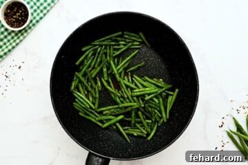 Crisp-tender green beans being stir-fried in a large skillet, ready for the Hunan Shrimp sauce.