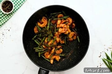 Shrimp and green beans tossed with the thickened Hunan sauce in a skillet, ready to be served.