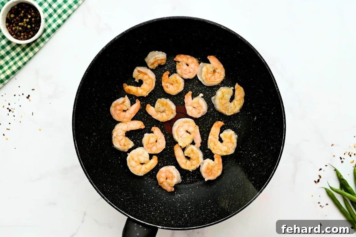Succulent shrimp, lightly coated in cornstarch, expertly stir-frying in a large pan until perfectly opaque and pink.