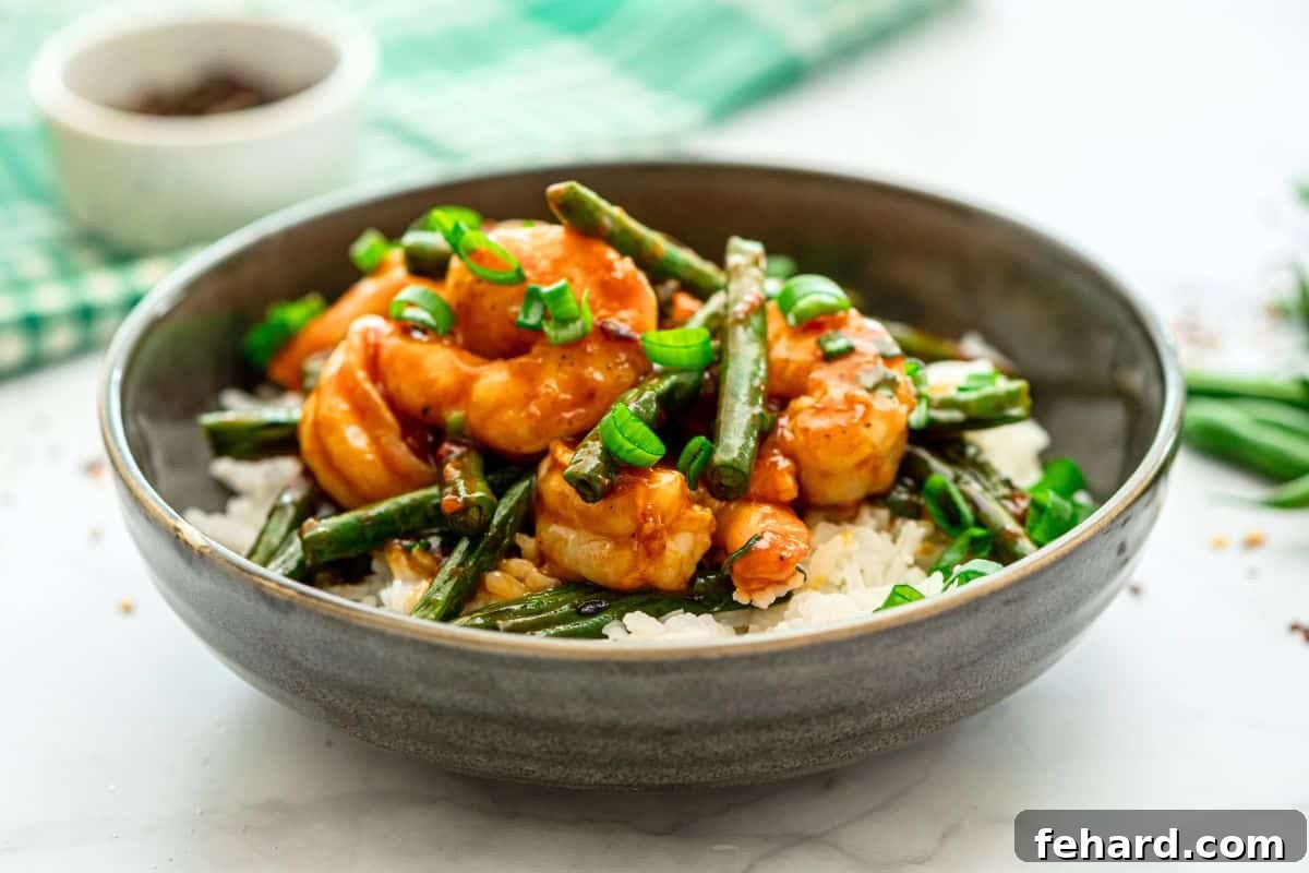 Homemade Hunan Shrimp stir-fry, presented beautifully with vibrant green beans over fluffy white rice, topped with fresh green onions for an inviting garnish.