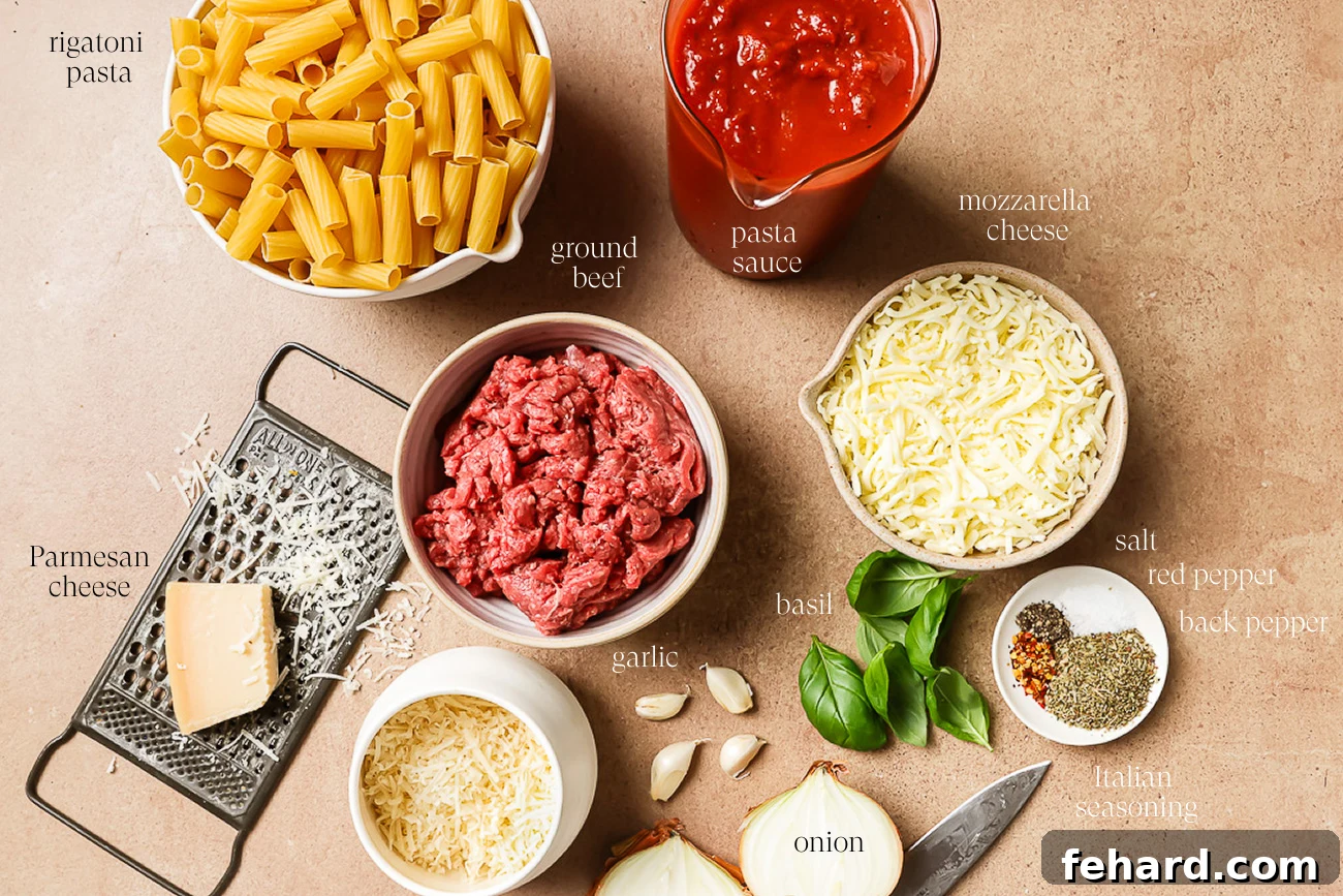 Top-down view of all necessary ingredients for Baked Rigatoni with Ground Beef, arranged on a rustic wooden surface. Includes uncooked rigatoni, ground beef, a jar of pasta sauce, shredded mozzarella, a block of Parmesan cheese with a grater, fresh garlic cloves, vibrant basil leaves, a halved onion, and various seasonings in small bowls.