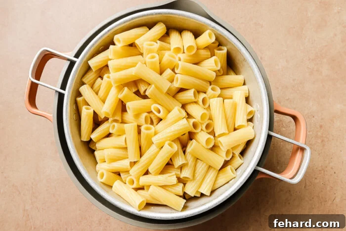 A colander full of perfectly cooked rigatoni pasta, ready for mixing into the meat sauce for baked rigatoni.