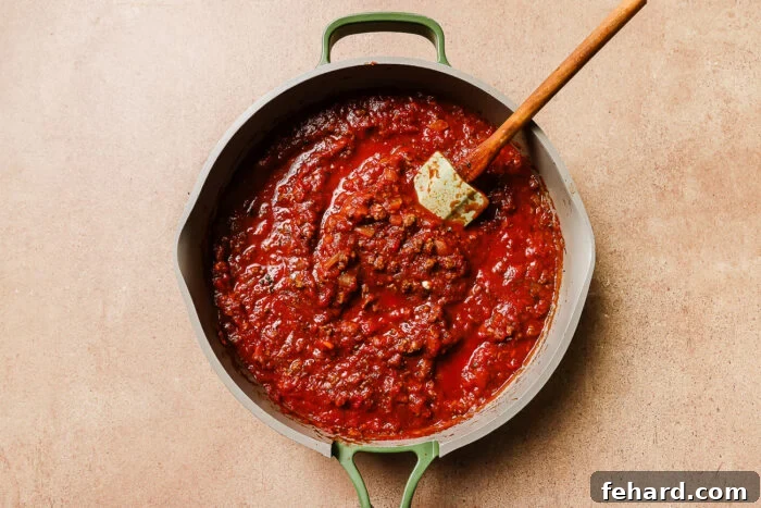 Rich tomato meat sauce simmering in a skillet, infused with ground beef, herbs, and spices, ready to be combined with pasta.