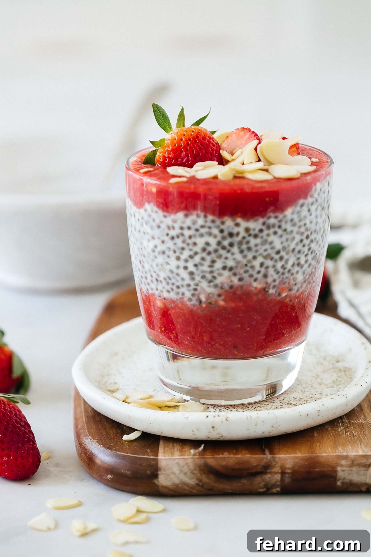 Luscious Strawberry Chia Delight 8 A beautifully presented cup of layered strawberry chia pudding, topped with fresh strawberry halves and almond slivers, showcasing its inviting appearance.