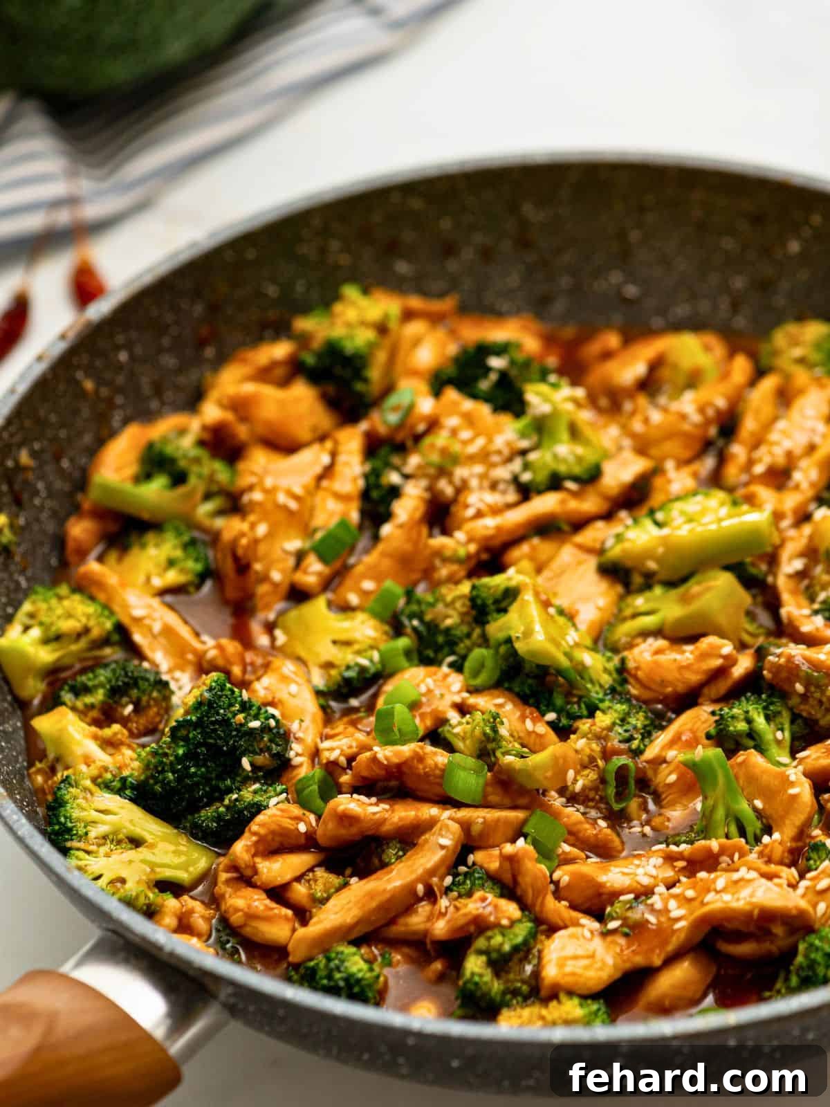 Chicken and Broccoli Stir Fry Broccoli and chicken in saute pan with savory brown sauce, garnished with sesame seeds.