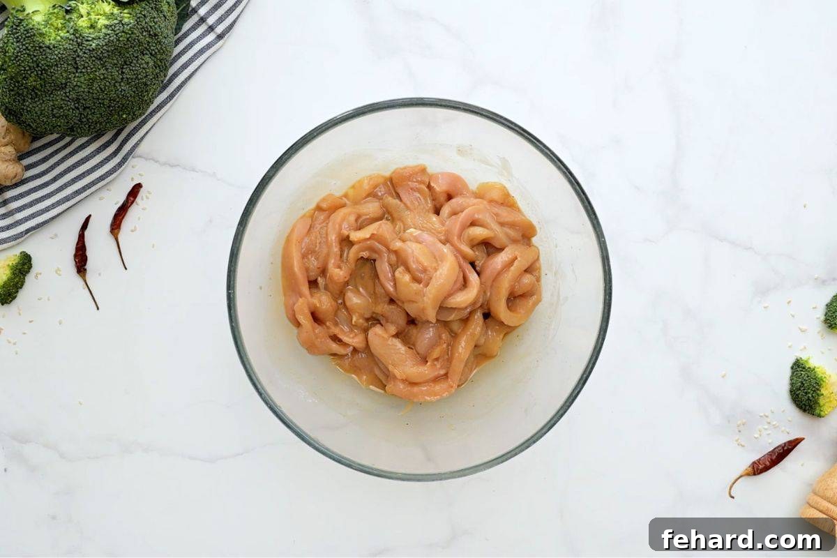 Stir Fry with Chicken and Broccoli Thinly sliced chicken breasts marinating in a savory sauce in a large mixing bowl, ready for stir-frying.