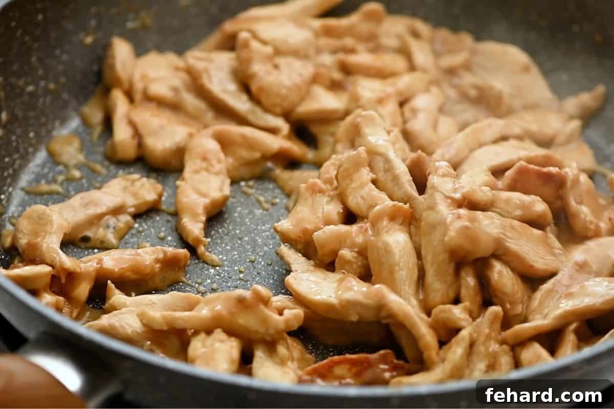 Quick Chicken Stir Fry with Broccoli Golden brown stir-fried chicken pieces cooking in a sauté pan before adding vegetables and sauce.