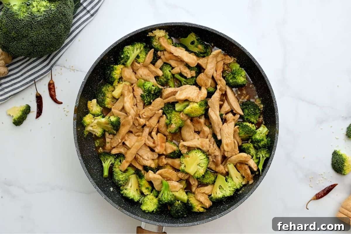 Quick Chicken Stir Fry with Broccoli Chicken and broccoli coated in a thick, savory brown sauce, simmering in a sauté pan until perfectly combined.