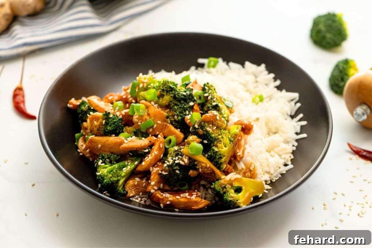 Broccoli Stir Fry with Chicken Platter of Chicken and Broccoli Stir Fry, garnished with sesame seeds and green onions, served alongside steamed white rice.