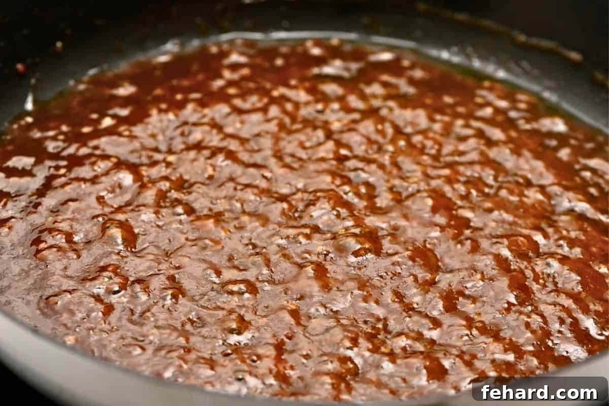 The honey soy sauce base for salmon bites actively thickening with cornstarch in a skillet, creating a rich, glossy glaze.