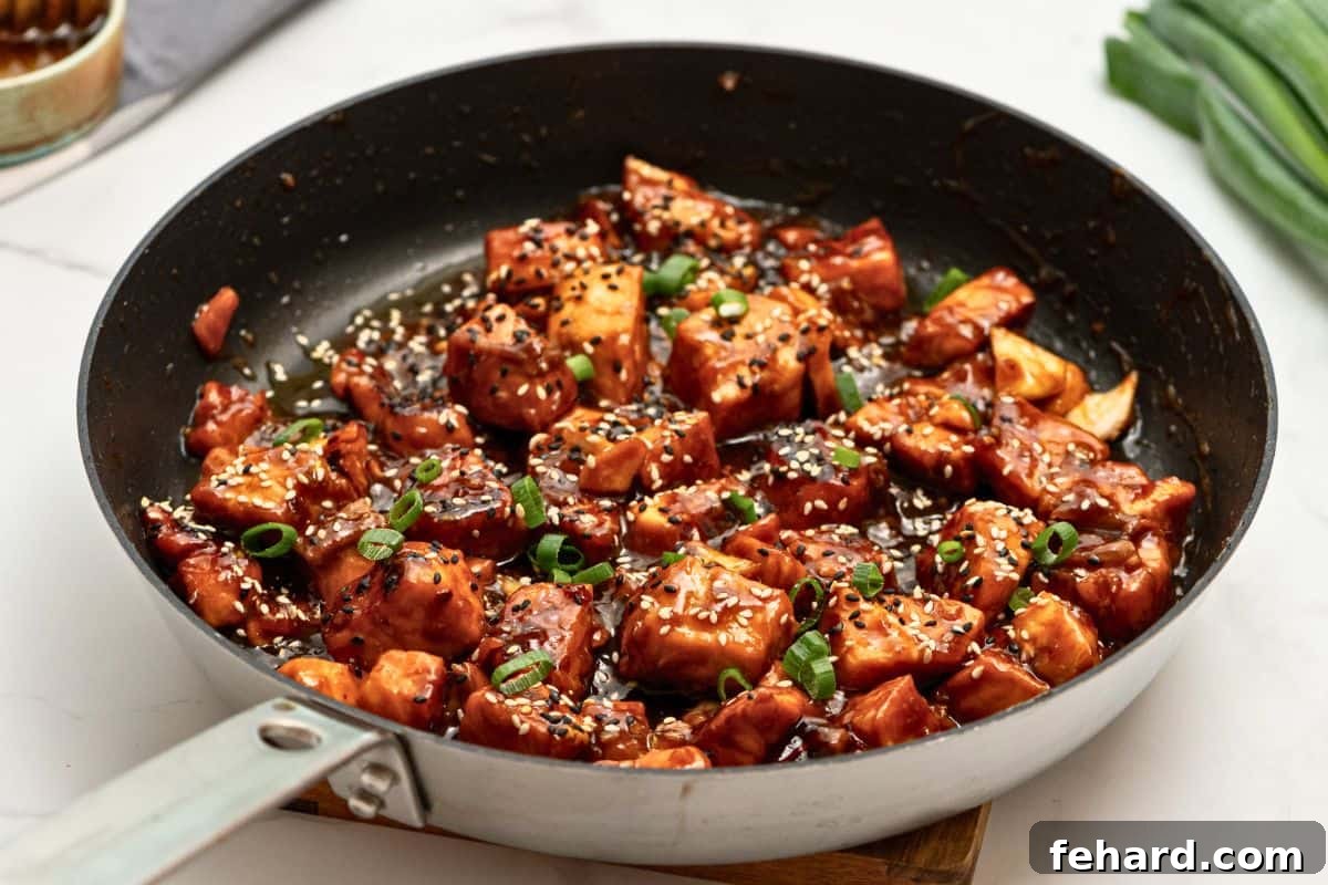 Cooked salmon bites generously coated in a sticky honey soy glaze, nestled within a skillet, ready to be served.