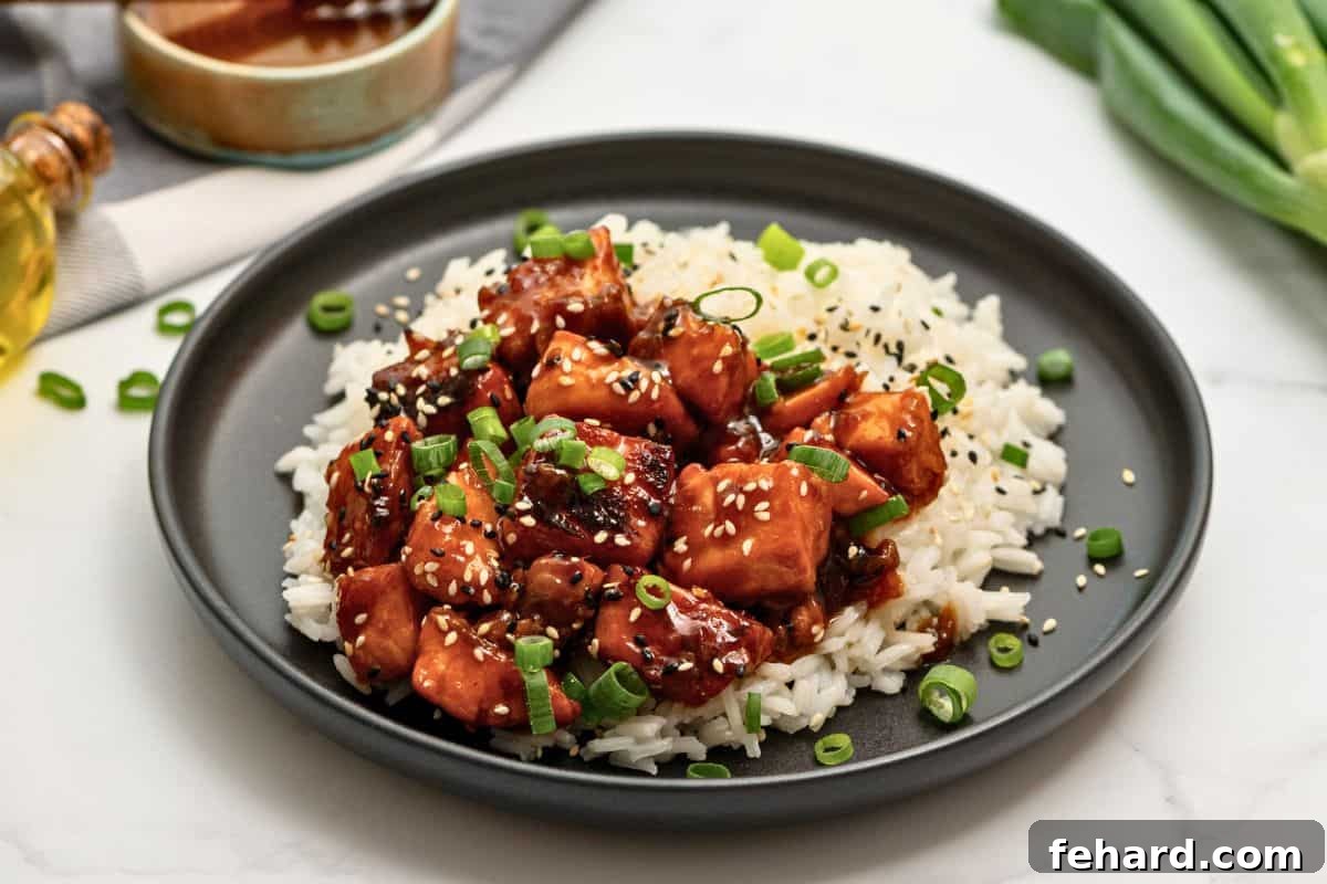 Beautifully presented Honey Soy Salmon Bites alongside a serving of white rice, garnished with vibrant green onions and toasted sesame seeds, ready for a delicious meal.