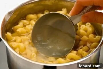 Creamy Cavatappi Perfection 4 A measuring cup collecting starchy pasta water from cooking cavatappi.