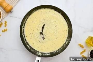 Creamy Cavatappi Perfection 5 Cream sauce with heavy cream and parmesan simmering in a skillet.