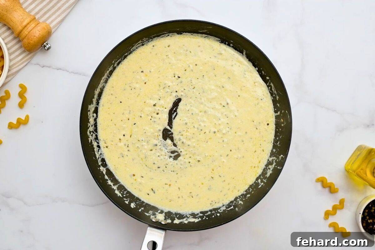 Recipe Cavatappi Pasta Sauce A rich, creamy parmesan sauce simmering in a skillet, ready for the cavatappi pasta.