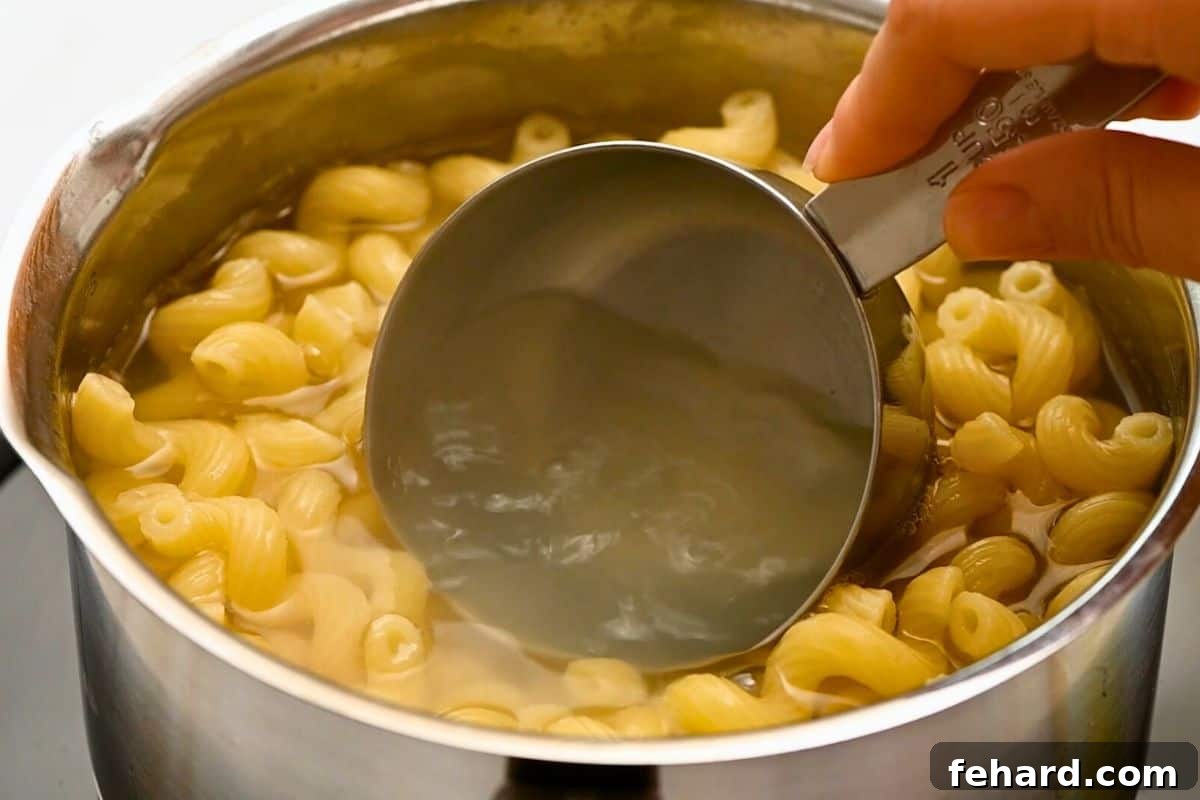 Cavatappi Recipe Pasta Water A measuring cup scooping out starchy pasta water from a pot of cooking cavatappi, essential for a perfect sauce.