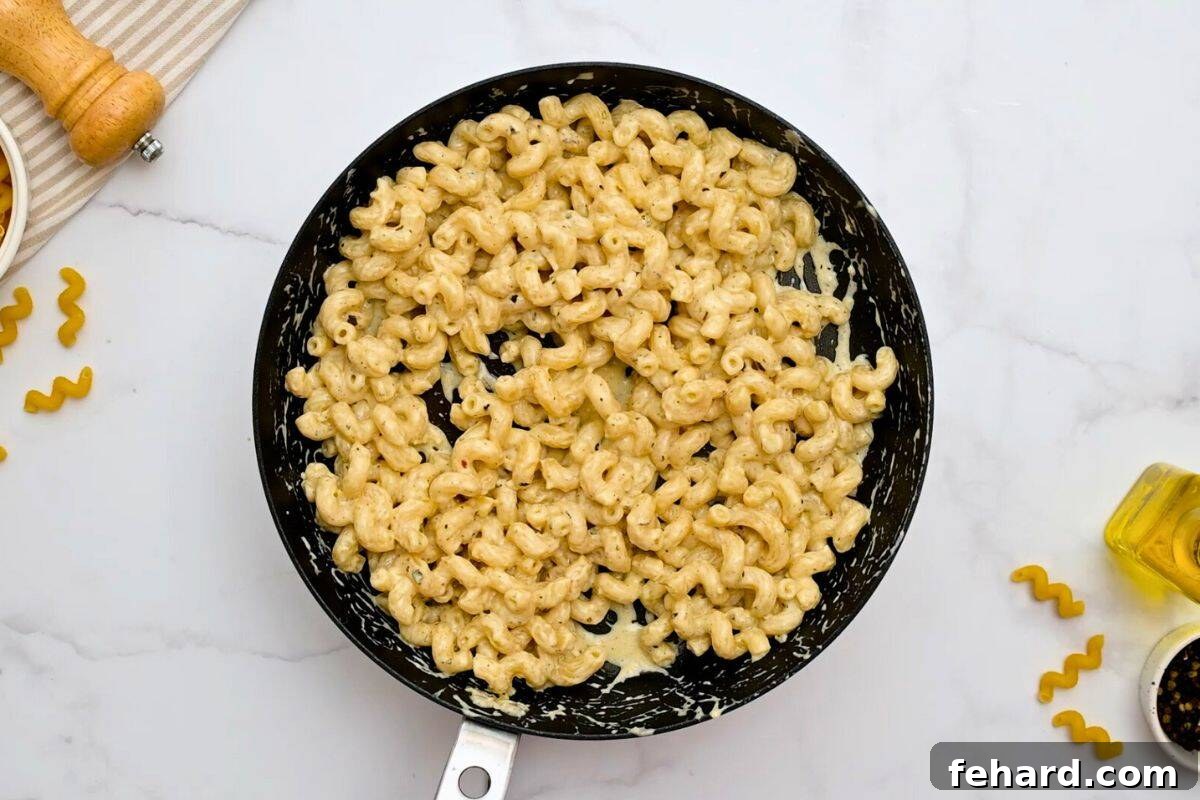 Easy Cavatappi Recipe Finished Tender cavatappi noodles beautifully coated in a rich, creamy parmesan sauce within a skillet, simmering gently.
